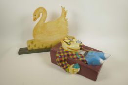A pop art carved wood figure of a dog lounging on a settee painted in bright colours, 12" long,