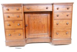 A C19th mahogany breakfront kneehole desk with a tooled leather inset top, central cupboard