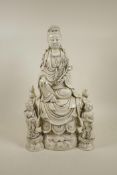 A Chinese blanc de chine porcelain figure of Quan Yin seated on a throne with two child
