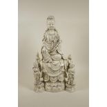 A Chinese blanc de chine porcelain figure of Quan Yin seated on a throne with two child