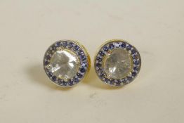 A pair of silver gilt stud earrings set with an uncut diamond encircled by sapphires