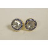 A pair of silver gilt stud earrings set with an uncut diamond encircled by sapphires