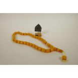 A string of Tibetan faux butterscotch amber mala beads, together with a Tibetan mounted metal