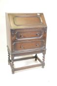 An early C20th Jacobean style oak bureau of small proportions, the fall front over two drawers,