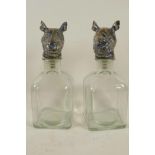 A pair of square glass decanters with metal stoppers in the form of a rhino head, 9½" high