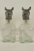 A pair of square glass decanters with metal stoppers in the form of a rhino head, 9½" high