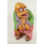 A South East Asian carved wood grotesque figure in brightly painted clothing, 16½" high