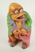 A South East Asian carved wood grotesque figure in brightly painted clothing, 16½" high