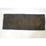 A textile wall hanging embroidered with Islamic calligraphy, in gilt metal wire, 63" x 24"
