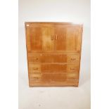 A mid century Heal's tall boy chest of two cupboards over three drawers, inset ivorine label to