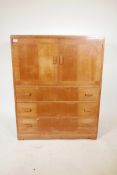 A mid century Heal's tall boy chest of two cupboards over three drawers, inset ivorine label to