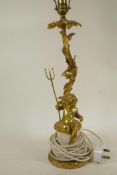 A gilt metal table lamp cast as a cherub with trident seated by a flowering branch, 20" high