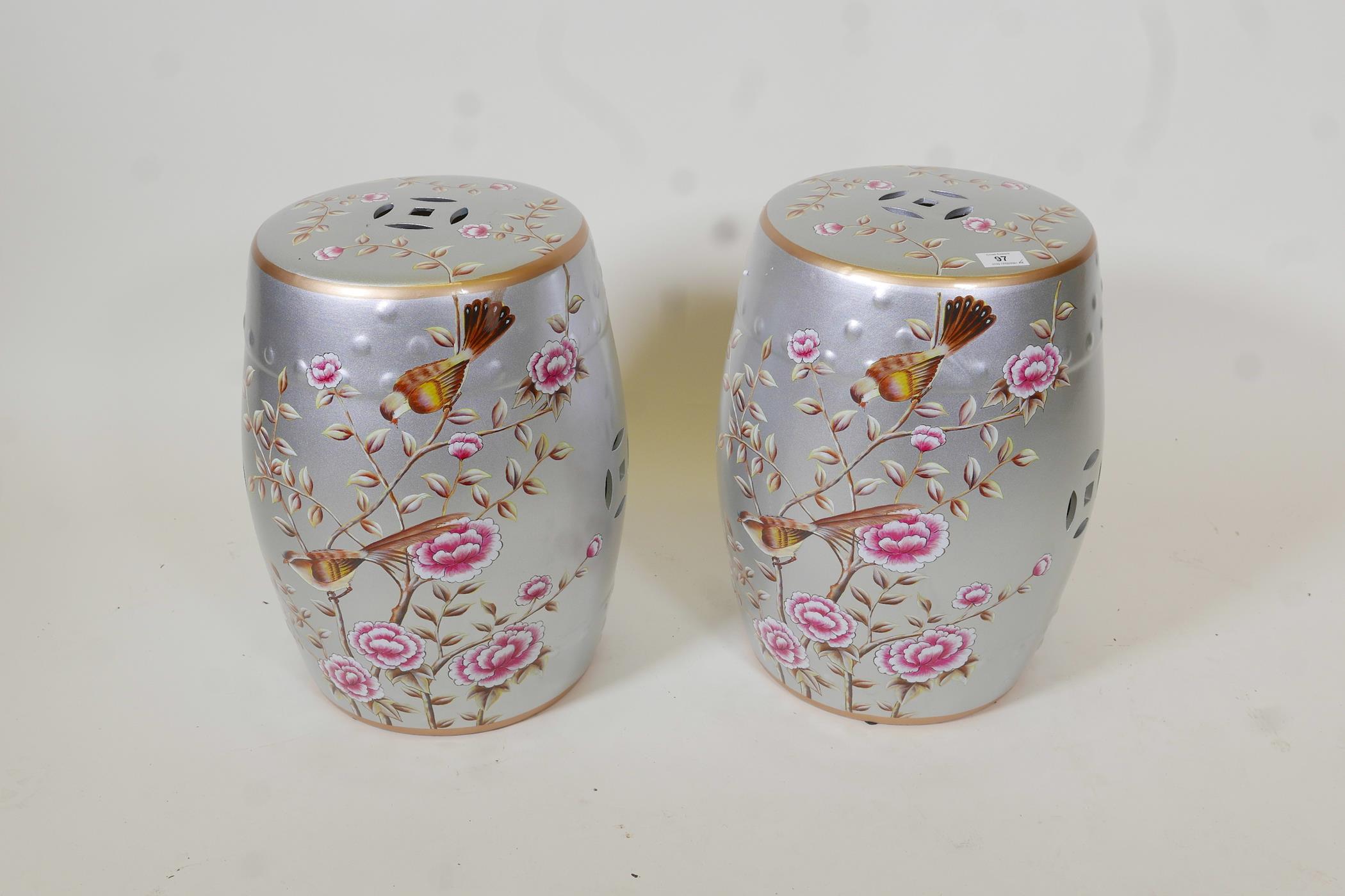 A pair of porcelain garden stools decorated with birds and flowers in bright enamels on a silver