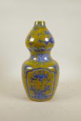 A Chinese porcelain double gourd vase with blue and white dragon and bird decoration on a yellow