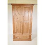 A pine two door wardrobe with a single drawer, raised on a plinth base, 43½" x 24½", 76" high