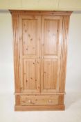 A pine two door wardrobe with a single drawer, raised on a plinth base, 43½" x 24½", 76" high