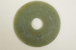 A Mughal green jade roundel with intricately carved calligraphy, 4" diameter