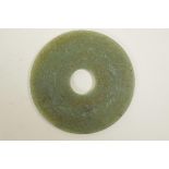 A Mughal green jade roundel with intricately carved calligraphy, 4" diameter