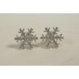 A pair of silver and cubic zirconium stud earrings in the form of snowflakes