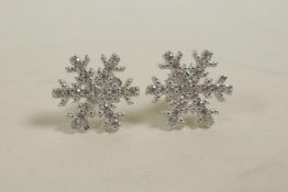 A pair of silver and cubic zirconium stud earrings in the form of snowflakes