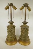 A pair of repousse decorated brass table lamps embossed with classical figures, 21" high