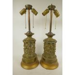 A pair of repousse decorated brass table lamps embossed with classical figures, 21" high