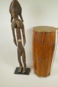 An African carved wood figure of a woman, 27½" high, together with a double skinned tribal drum