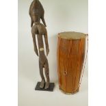 An African carved wood figure of a woman, 27½" high, together with a double skinned tribal drum