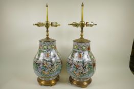 A pair of Chinese famille verte porcelain table lamps of bulbous form decorated with figures in a