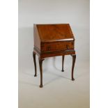 A Queen Anne style walnut fall front bureau, with fitted interior over single drawer, raised on