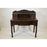 A Chinese carved hardwood desk, the raised upper section with two small cupboards and pigeon