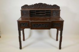 A Chinese carved hardwood desk, the raised upper section with two small cupboards and pigeon