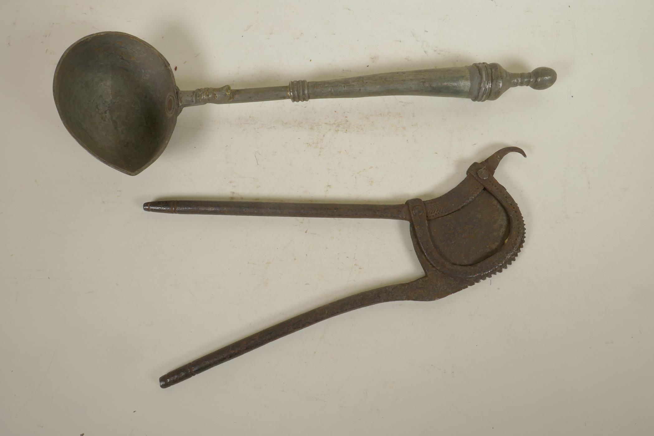 An antique Indian iron betel nut cutter, together with a metal oil ladle, 16" longest