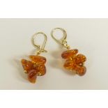 A pair of natural amber beaded earrings with yellow metal mounts