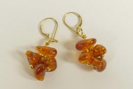 A pair of natural amber beaded earrings with yellow metal mounts