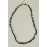 A string of black cultured pearls with 14ct gold clasp, 17" long