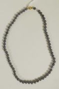 A string of black cultured pearls with 14ct gold clasp, 17" long