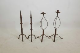 A pair of wrought iron candlesticks on tripod feet, and a pair of similar fire dogs, 22" high