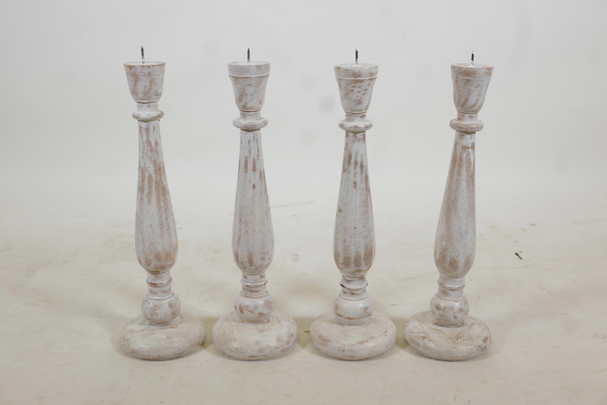 A set of four turned and painted wood pricket candlesticks with a distressed finish, 19" high