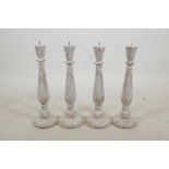 A set of four turned and painted wood pricket candlesticks with a distressed finish, 19" high