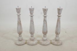 A set of four turned and painted wood pricket candlesticks with a distressed finish, 19" high