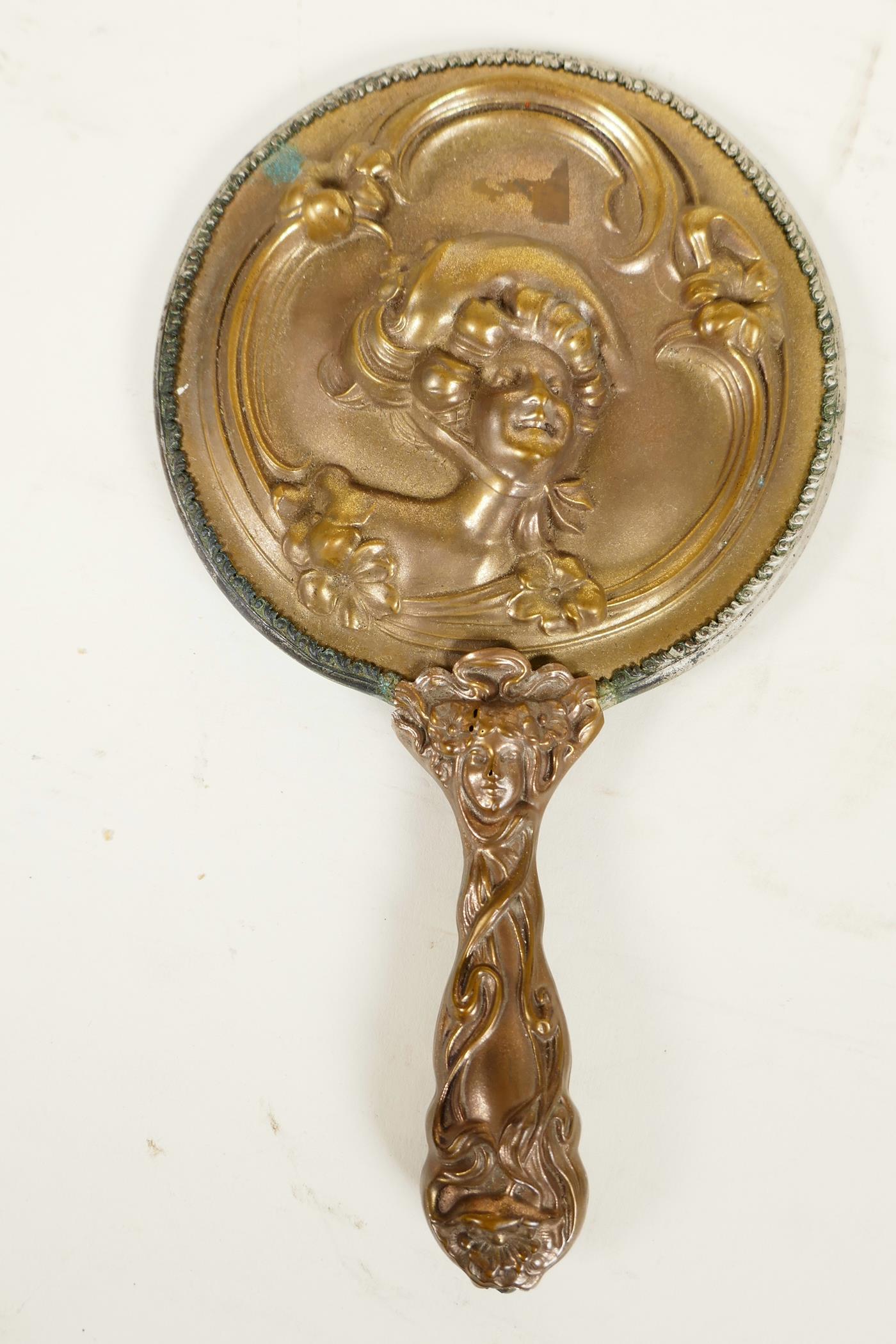 A C19th Art Nouveau bronze hand mirror embossed with scrolls and faces, and bejewelled glass mirror,