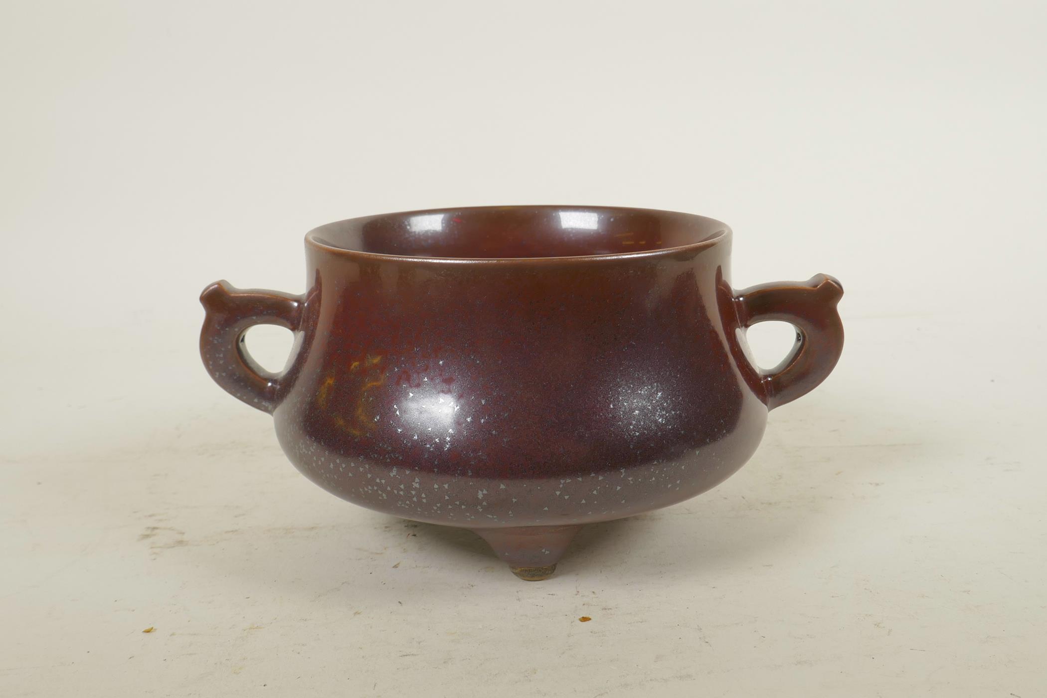 A Chinese copper glazed porcelain censer with two handles, raised on tripod supports, impressed seal