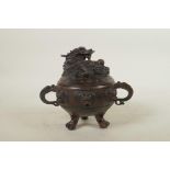 A Chinese bronze censer and cover with two dragon shape handles, tripod pawed feet, dragon mask