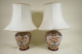 A pair of Chinese pottery table lamps on wood stands with white silk shades, 20" high