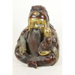 A Chinese gilt and red bronze figure of a bearded Lohan with small child in his arm, 9" high