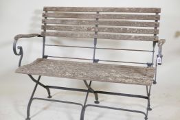 A wrought steel and teak slatted two seater folding garden bench labelled Smith and Hawken, Mill