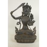 A Chinese bronze figure of a Buddhist deity holding a sword and seated in meditation on a lotus