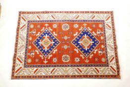 An Oriental red ground wool rug with twin blue medallion design, 48" wide