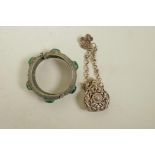 A Chinese white metal bangle set with green jade stones and a white metal scent holder pendant,